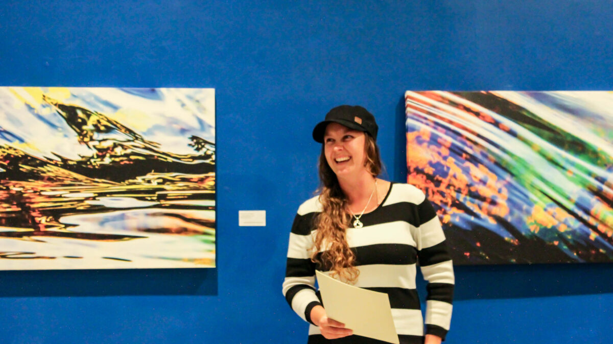 lynn stevens standing infront of her artwork at the island mountain arts gallery in Wells, BC